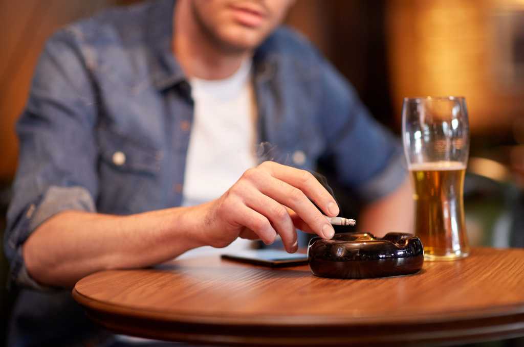 Bad habits: man sits smoking and drinking at a table...