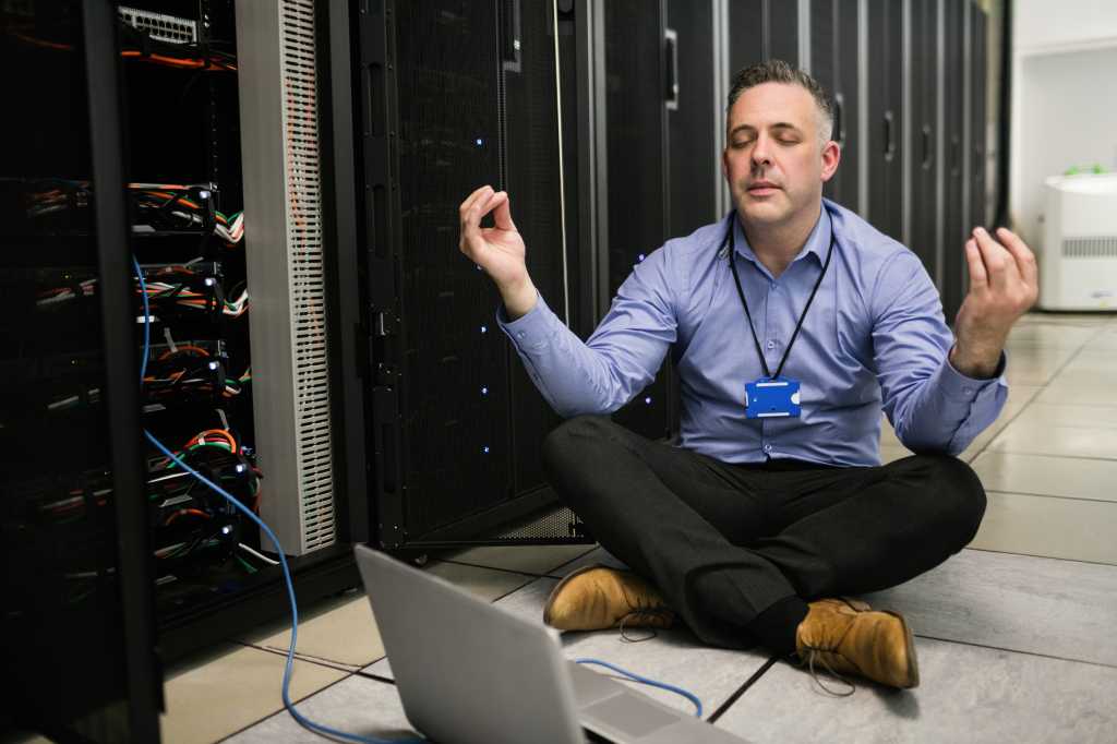 IT technician meditating on the floor of a server room or data center