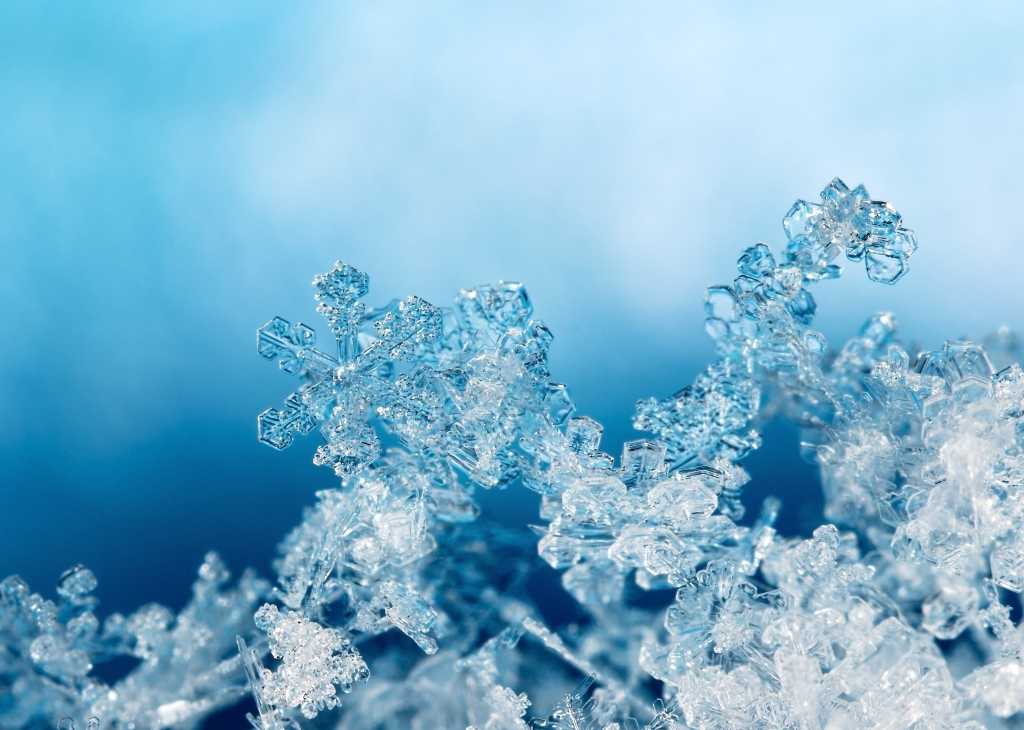 shutterstock 757358335 snowflakes on snow against clouds and blue sky natural snowflakes on snow