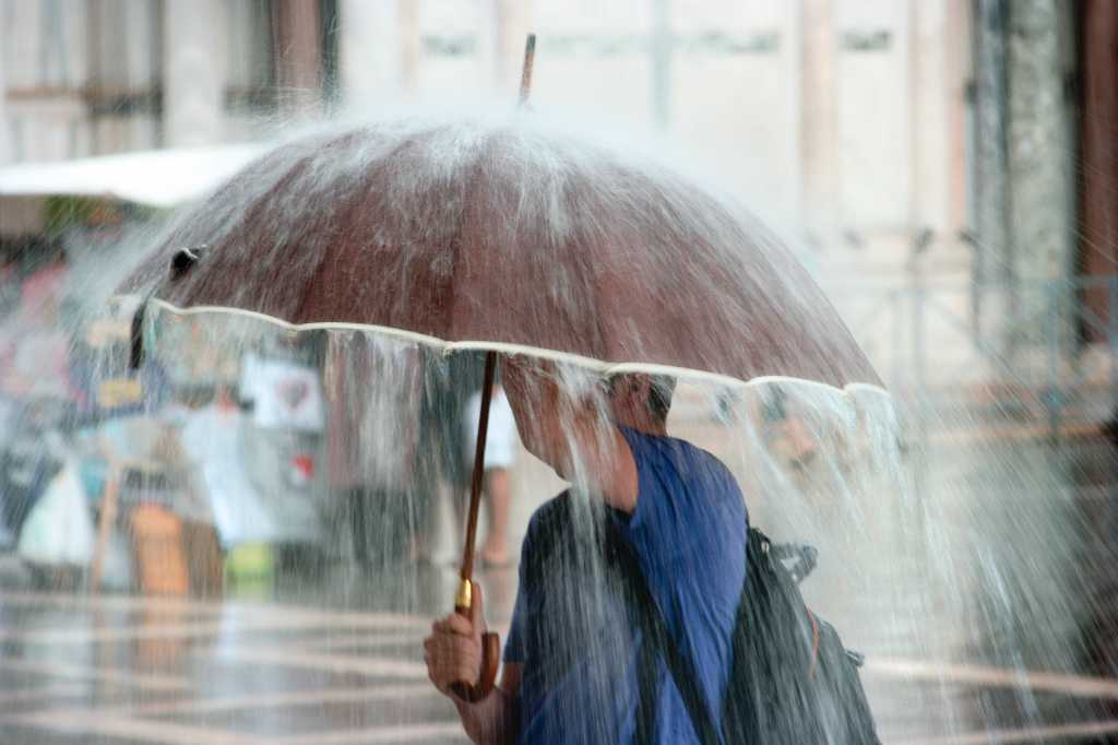 Cloud gotchas. Person under umbrella in the rain.